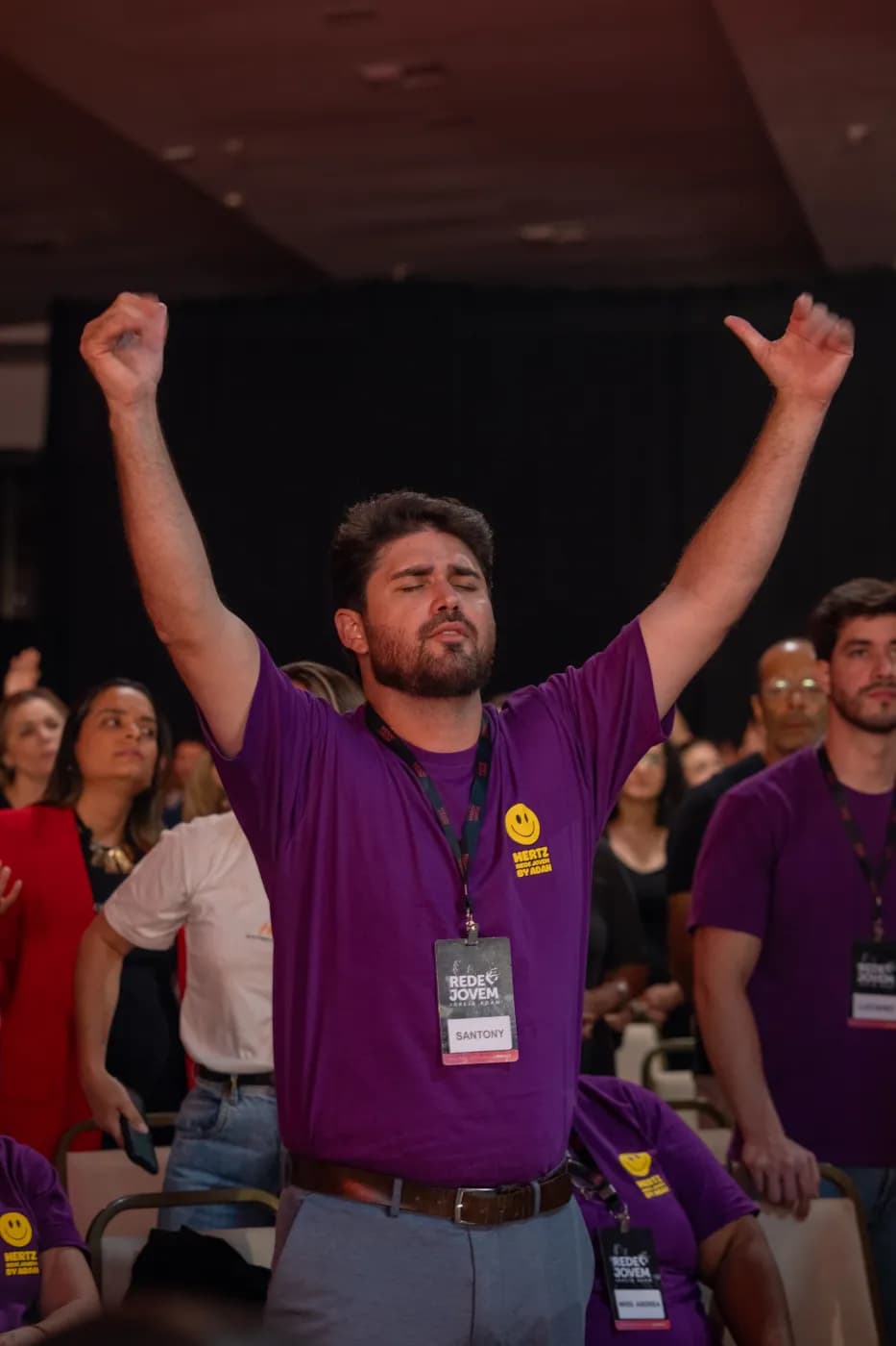 Participante adorando com os braços erguidos na Conferência Hertz 2025