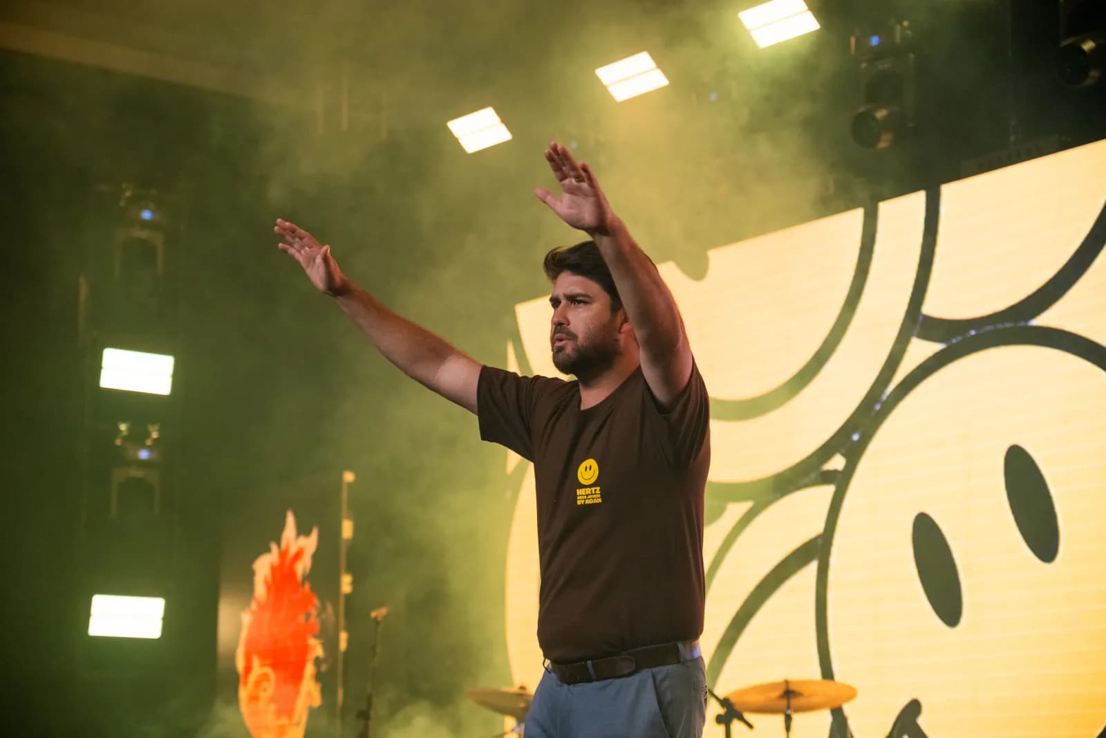Líder adorando com os braços erguidos no palco da Conferência Hertz