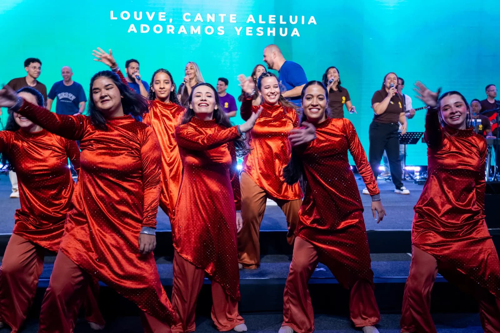 Equipe de dança celebrando no palco da Conferência Hertz 2025