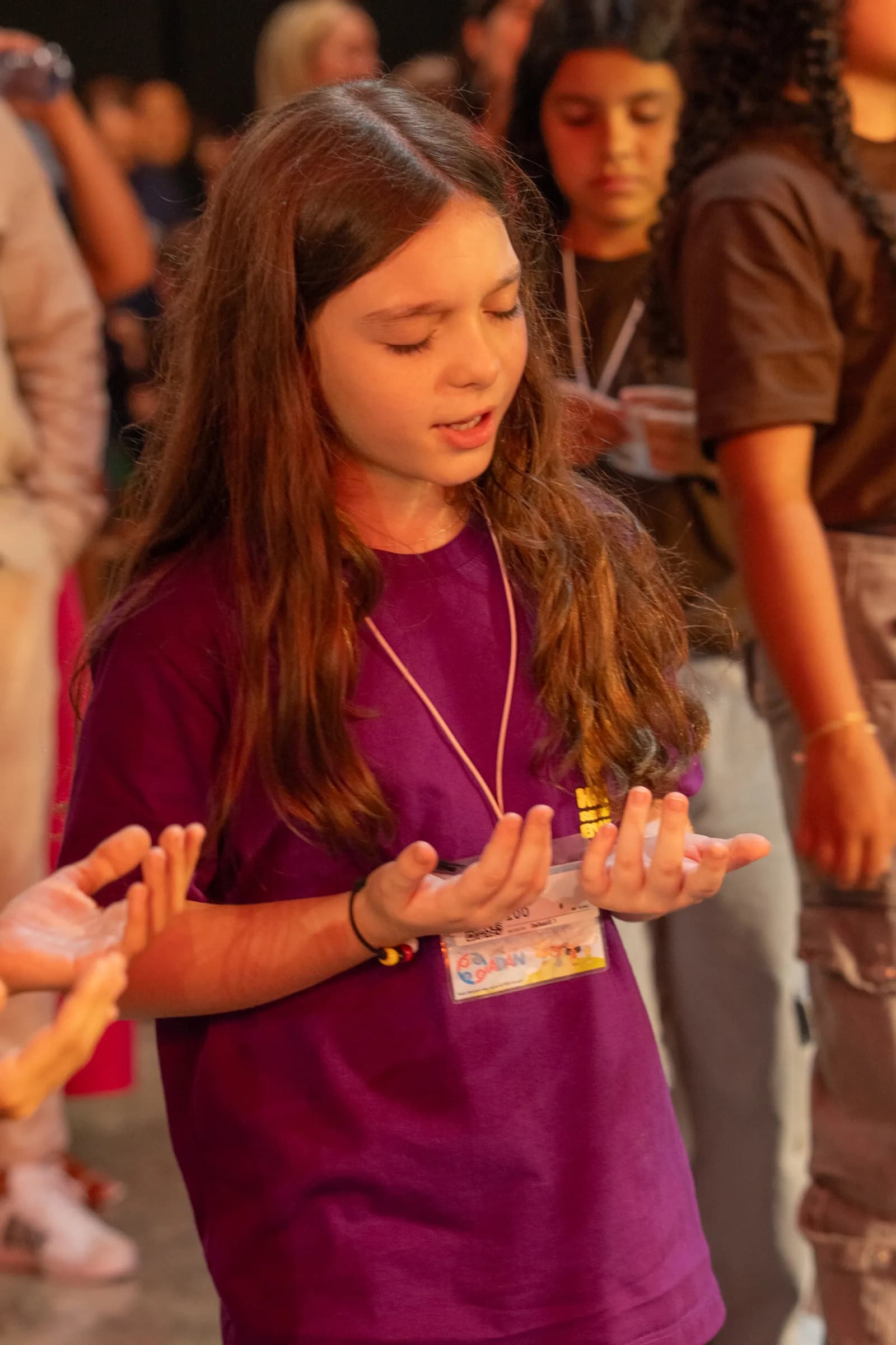 Menina adorando de olhos fechados e mãos erguidas na Hertz Kids 2025